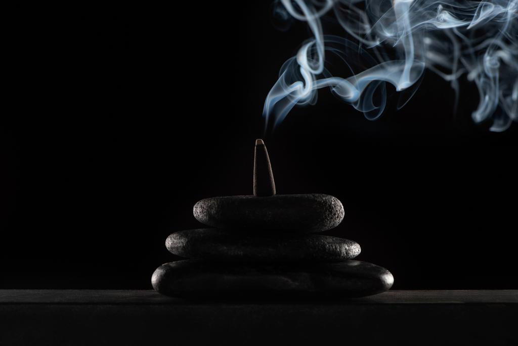 het verbranden van wierook op stenen met rook op zwarte achtergrond - Foto, afbeelding