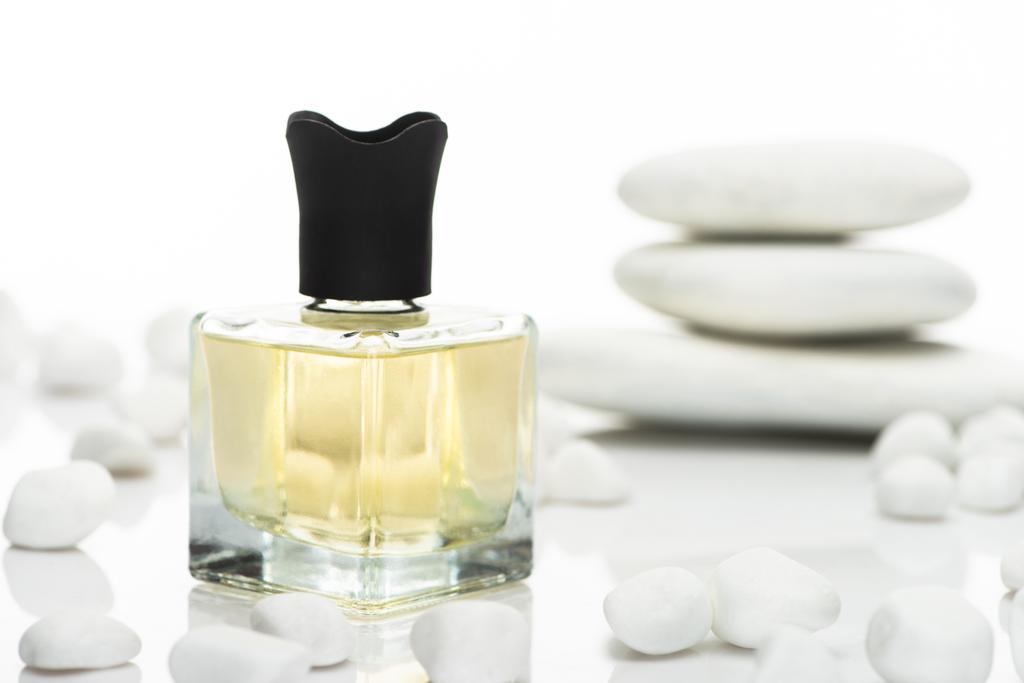 enfoque selectivo de perfume casero en botella cerca de piedras de spa sobre fondo blanco
 - Foto, imagen