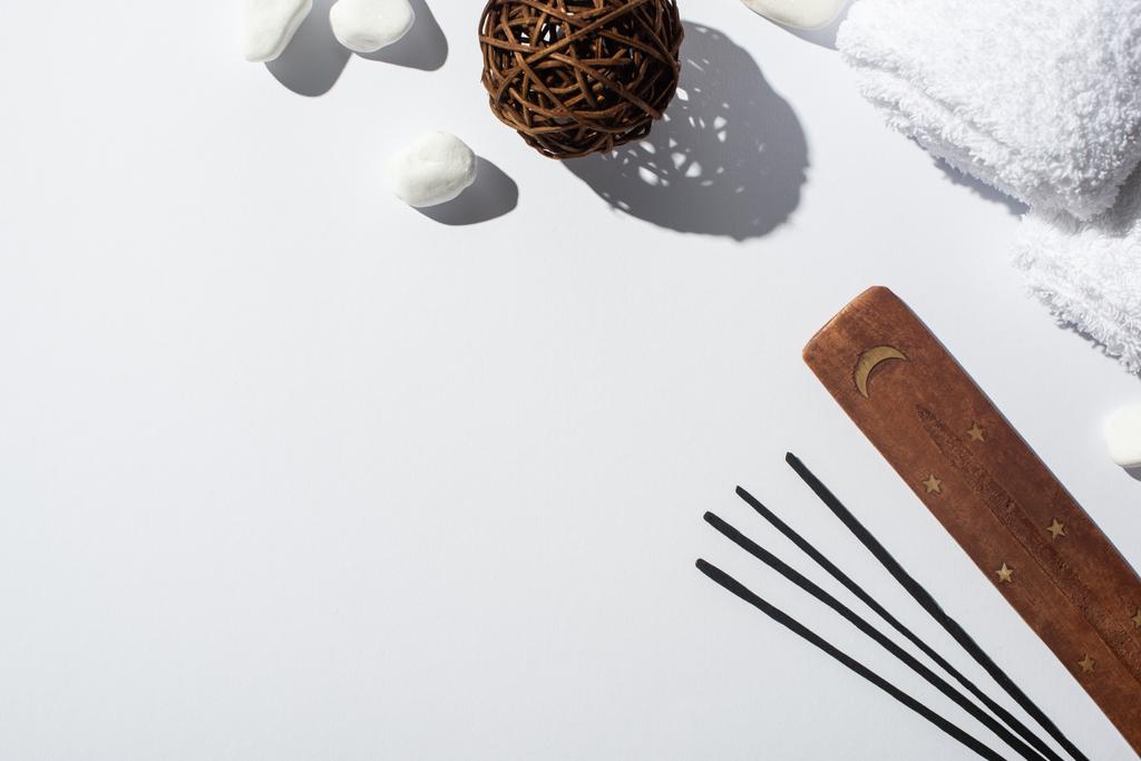 vista superior de palos de aroma, soporte de madera, piedras, toallas de algodón y bola decorativa sobre fondo blanco
 - Foto, imagen