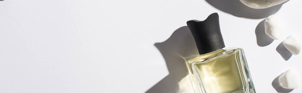 top view of perfume in bottle near stones on white background, panoramic shot - Photo, Image