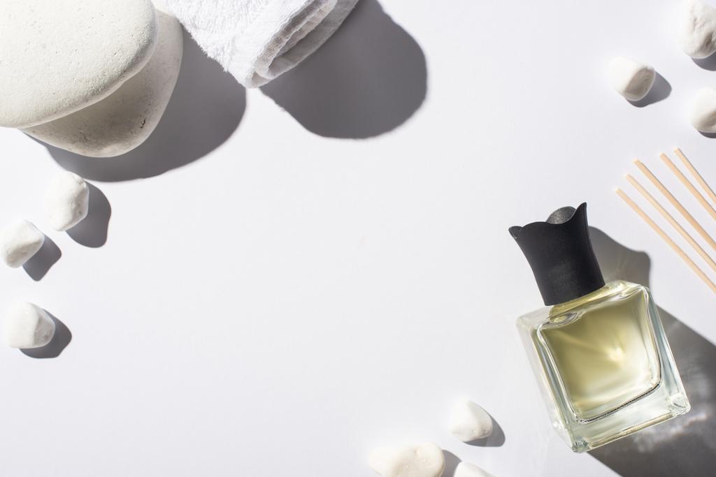 felső kilátás aroma pálcikák parfüm palackban közelében spa kövek és törölköző fehér háttér - Fotó, kép