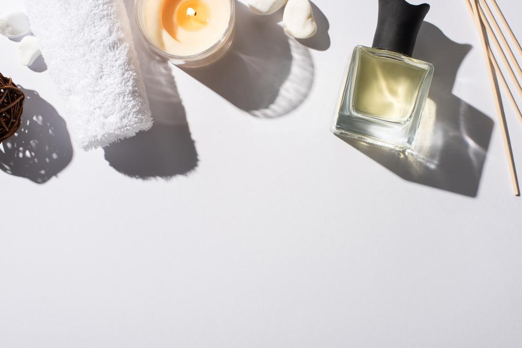 top view of aroma sticks with perfume in bottle near cotton towel, stones and candle on white background - Photo, Image