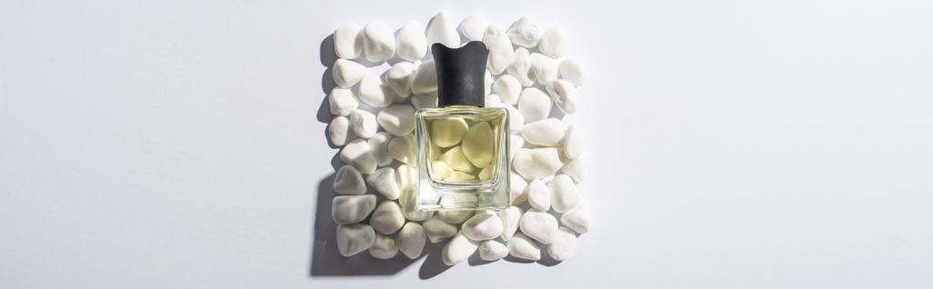 Draufsicht auf das Parfüm in der Flasche auf einem Quadrat aus Steinen auf weißem Hintergrund, Panoramaaufnahme - Foto, Bild