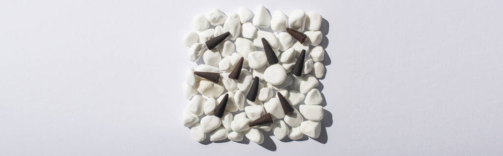 vista superior de cones de incenso em quadrado feito de pedras sobre fundo branco, tiro panorâmico
 - Foto, Imagem