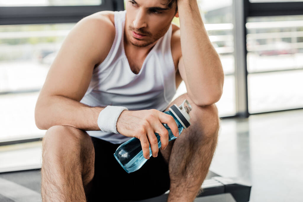 Müder Sportler hält Sportflasche mit Wasser  - Foto, Bild
