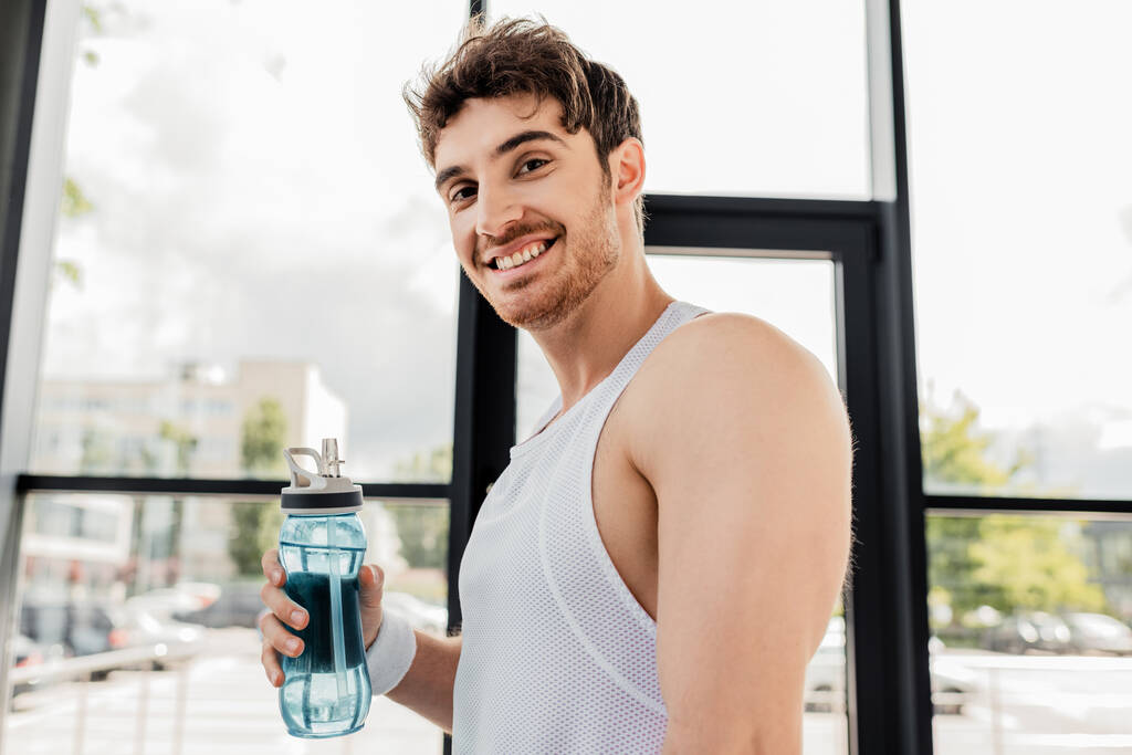счастливый спортсмен держит спортивную бутылку с водой
 - Фото, изображение