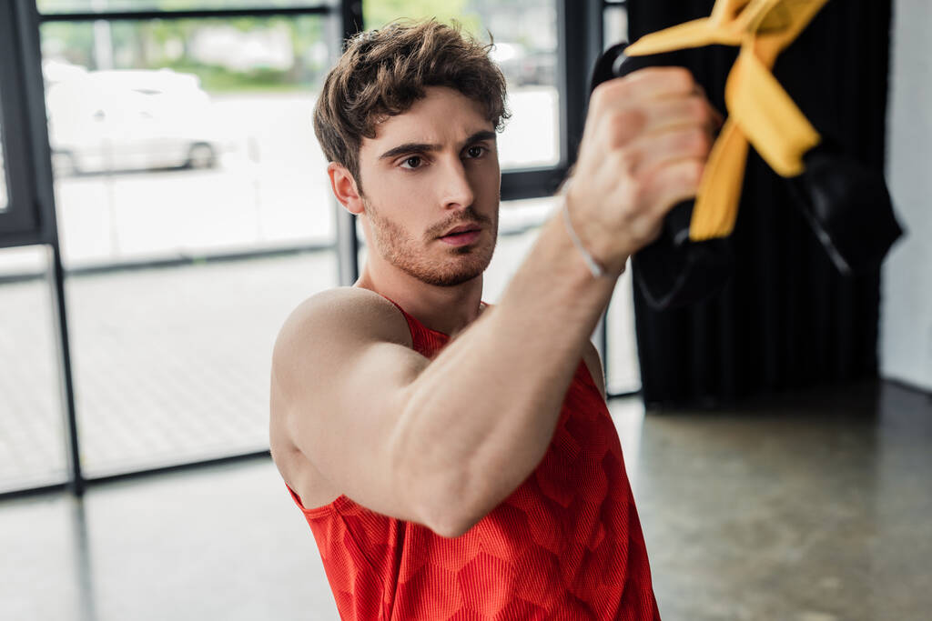 επιλεκτική εστίαση του αθλητικού άνδρα που γυμνάζεται με ελαστικά στο γυμναστήριο  - Φωτογραφία, εικόνα