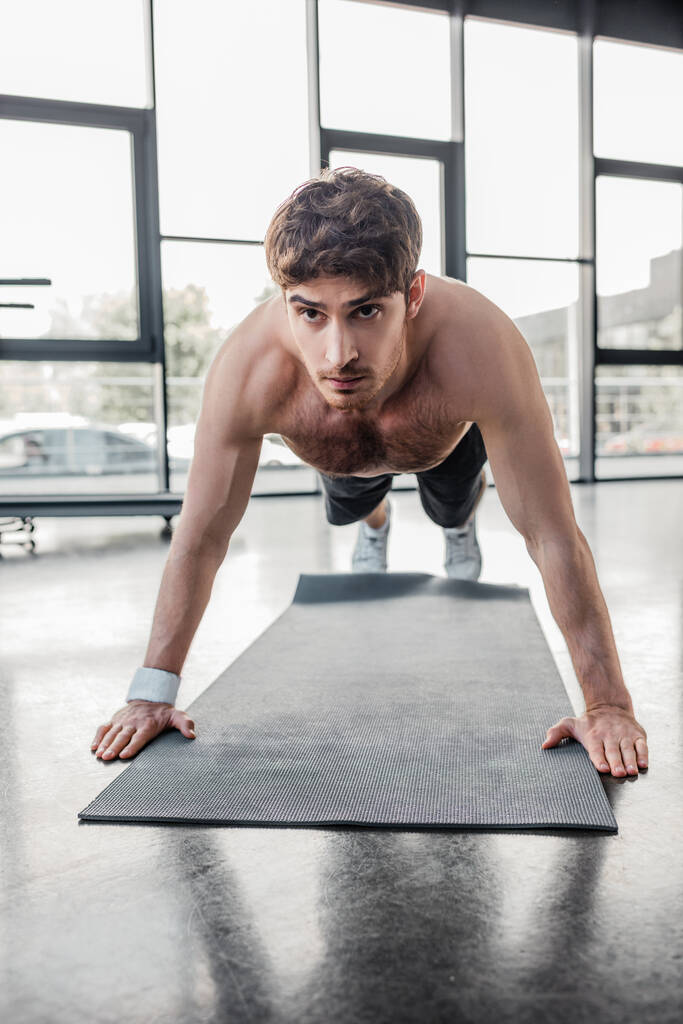 félmeztelen sportoló gyúr fitnessz szőnyegen tornateremben  - Fotó, kép