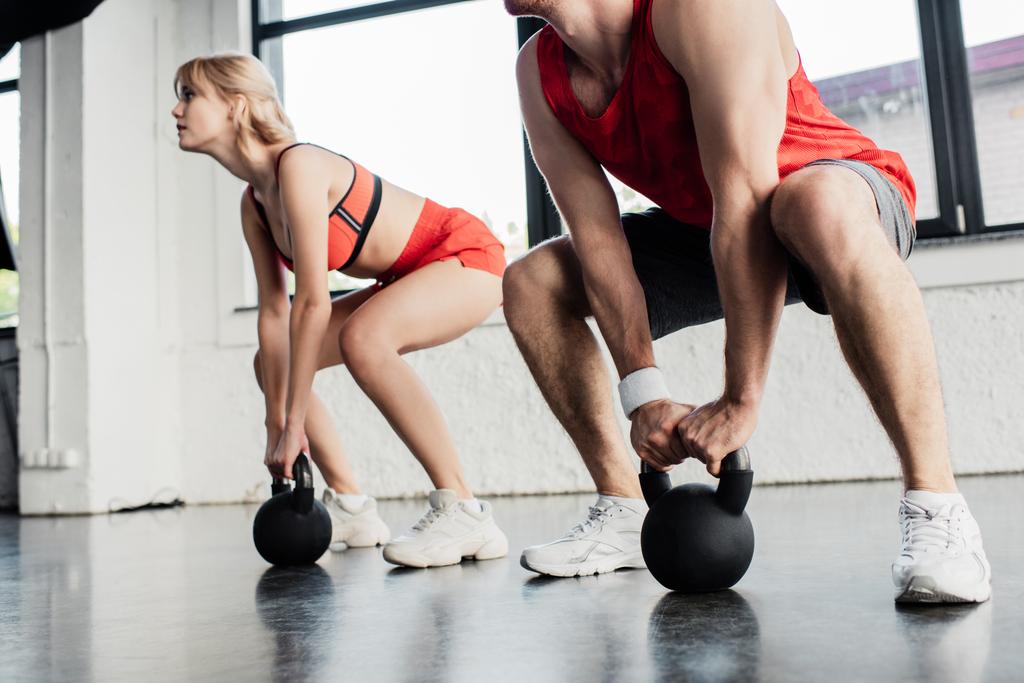 selektywne skupienie uwagi pary sportowej ćwiczącej z ciężkimi hantlami na siłowni  - Zdjęcie, obraz