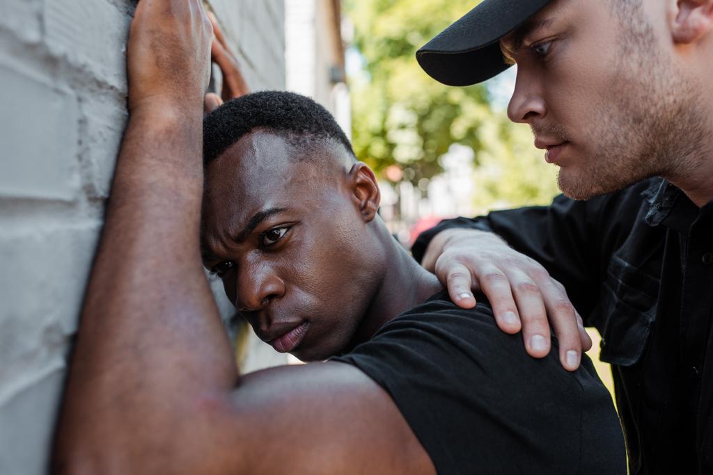 selektivní zaměření policisty v čepici zadržování afrického Američana na ulici, rasismus  - Fotografie, Obrázek