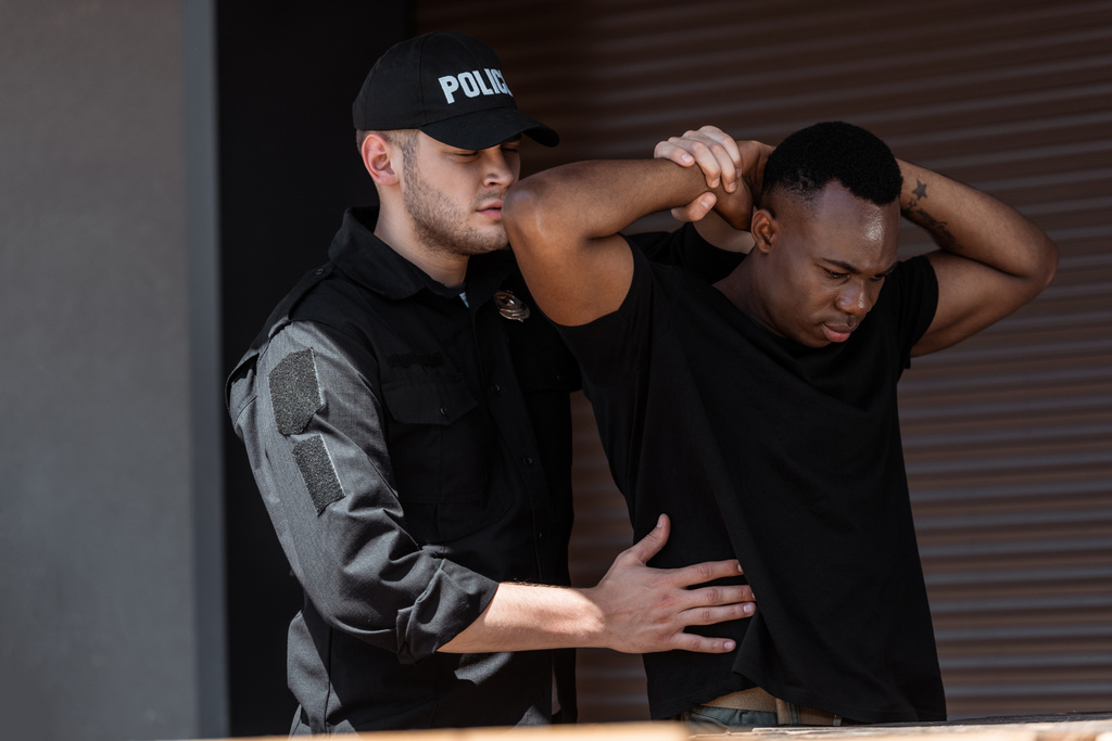 agente di polizia in berretto con lettere della polizia trattenere l'uomo africano americano - Foto, immagini