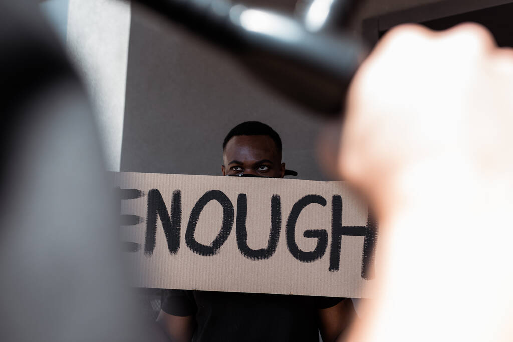 selektivní zaměření afroamerického muže se šátkem na obličeji držícího plakát s dostatečným písmem v blízkosti policisty, rasismus koncept  - Fotografie, Obrázek