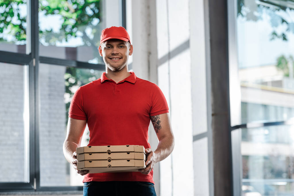 щасливий чоловік доставки в кепці і уніформі тримає коробки для піци
  - Фото, зображення