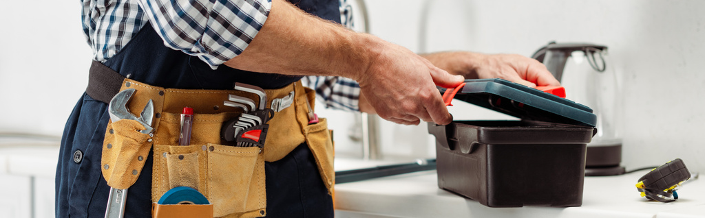 Aussichtsreiche Ernte des Klempners in Werkzeuggürtel Werkzeugkasten auf Arbeitsplatte in der Küche öffnen  - Foto, Bild