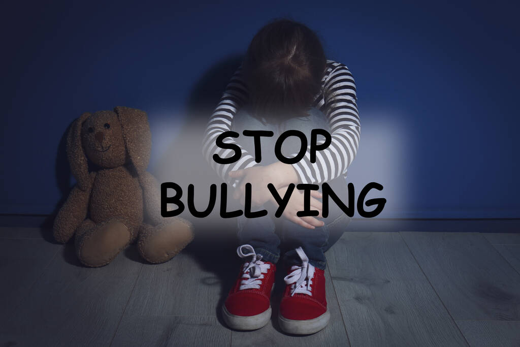 Message STOP BULLYING et la petite fille maltraitée pleurer près du mur bleu - Photo, image
