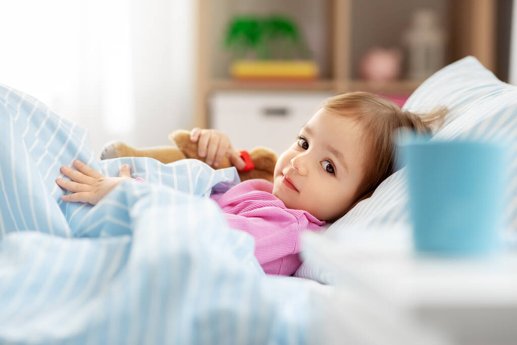 маленька дівчинка лежить в ліжку вдома
 - Фото, зображення