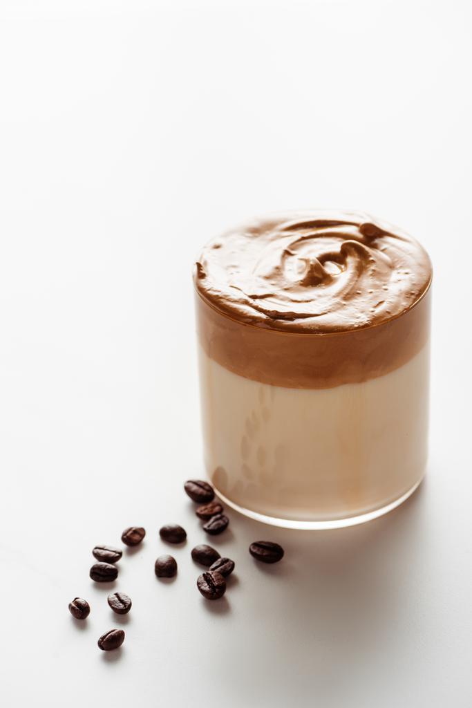 おいしいダルゴナコーヒー白を背景にコーヒー豆の近くのガラス - 写真・画像