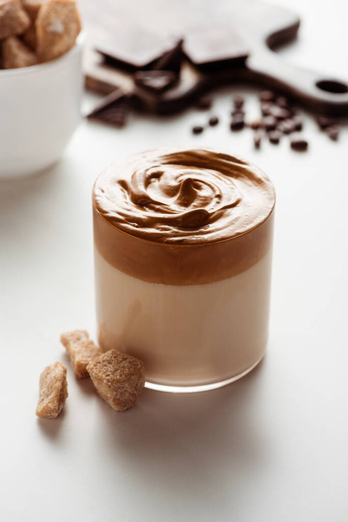 szelektív fókusz ízletes Dalgona kávé üveg közel barna cukor fehér alapon - Fotó, kép