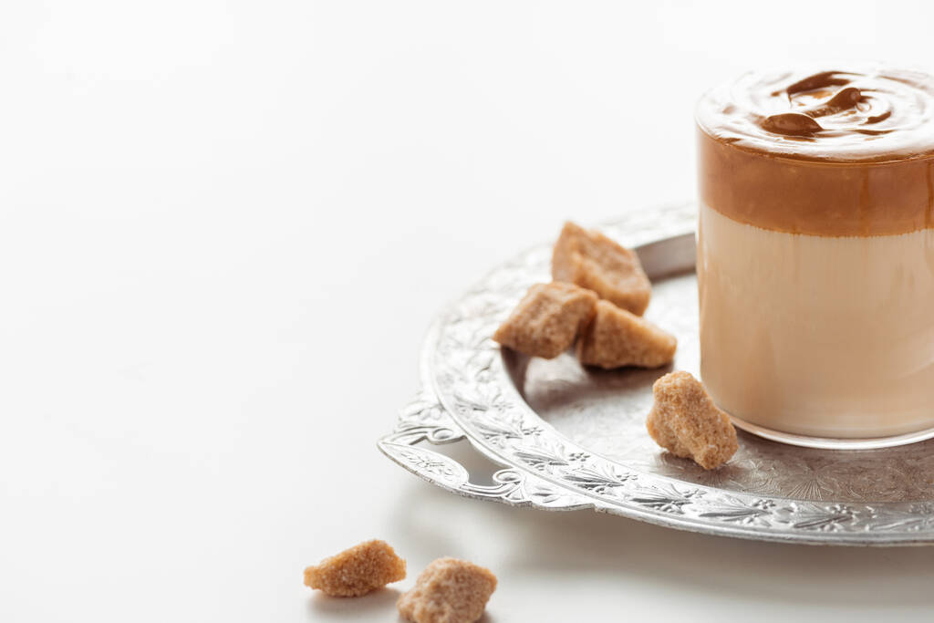 смачна кава Далгона в склянці біля коричневого цукру на срібному підносі на білому тлі
 - Фото, зображення
