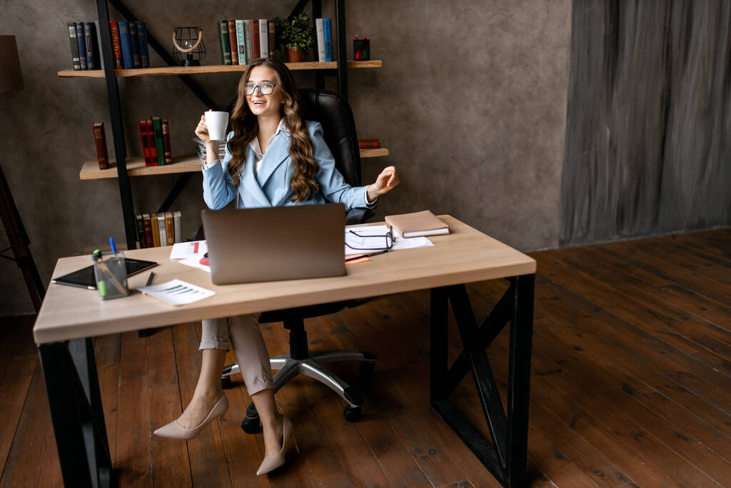 молодая женщина работает в офисе с ноутбуком
  - Фото, изображение