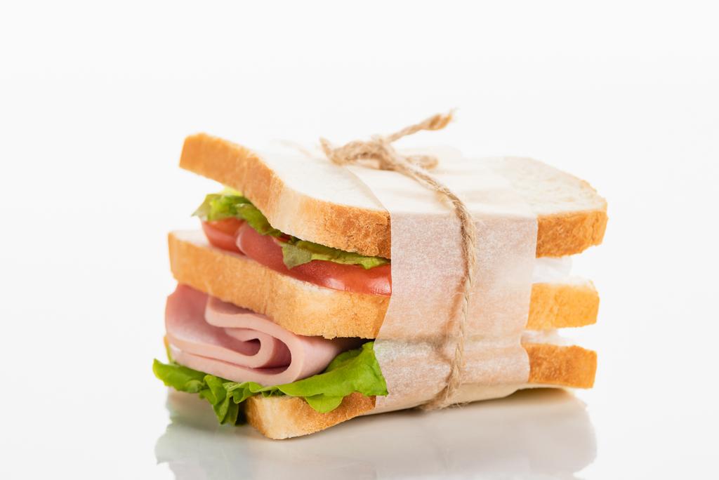 delicioso sándwich fresco con salchicha en rodajas y lechuga en la superficie blanca
 - Foto, Imagen