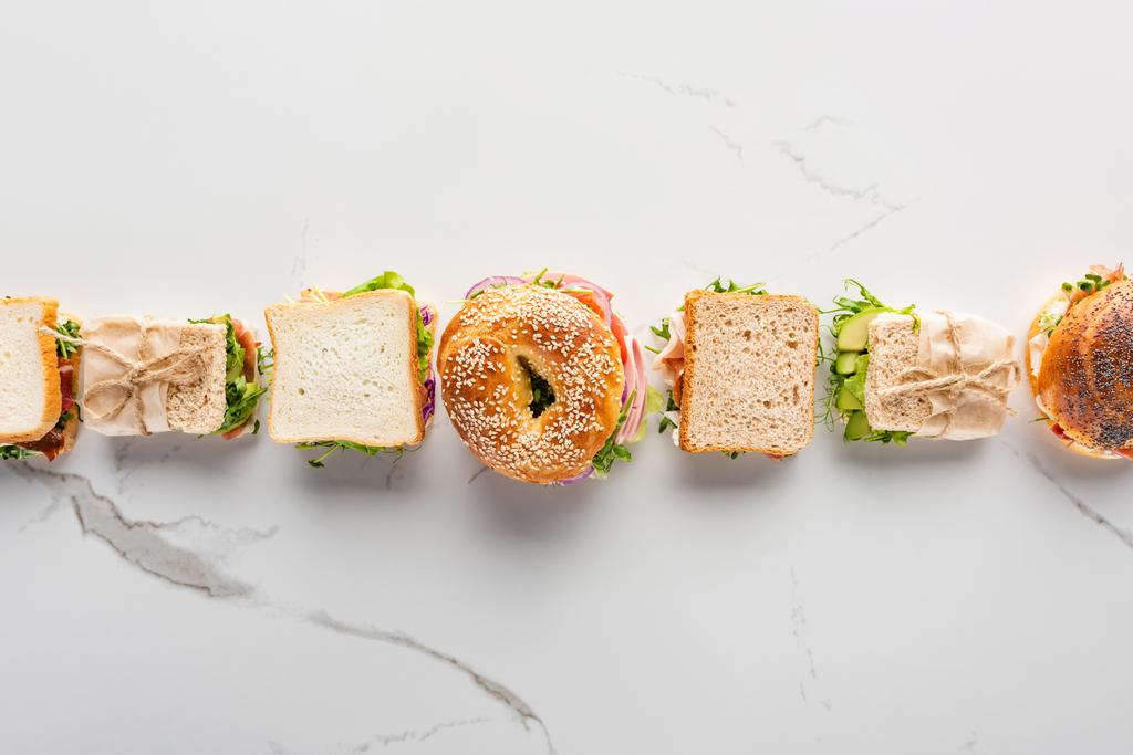 flat lay with fresh sandwiches and bagel on marble white surface - Photo, Image