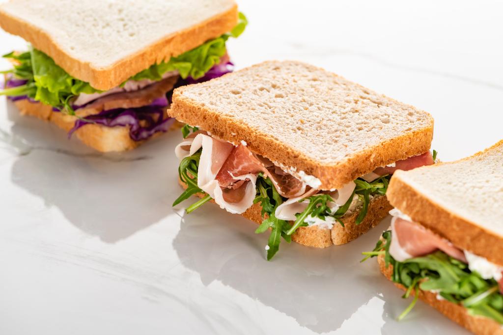 φρέσκα σάντουιτς με ρόκα και κρέας σε λευκή μαρμάρινη επιφάνεια - Φωτογραφία, εικόνα