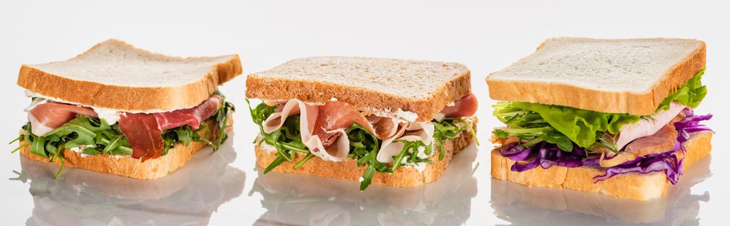 čerstvé zelené sendviče s avokádem a jamonem na mramorovém bílém povrchu, panoramatický záběr - Fotografie, Obrázek