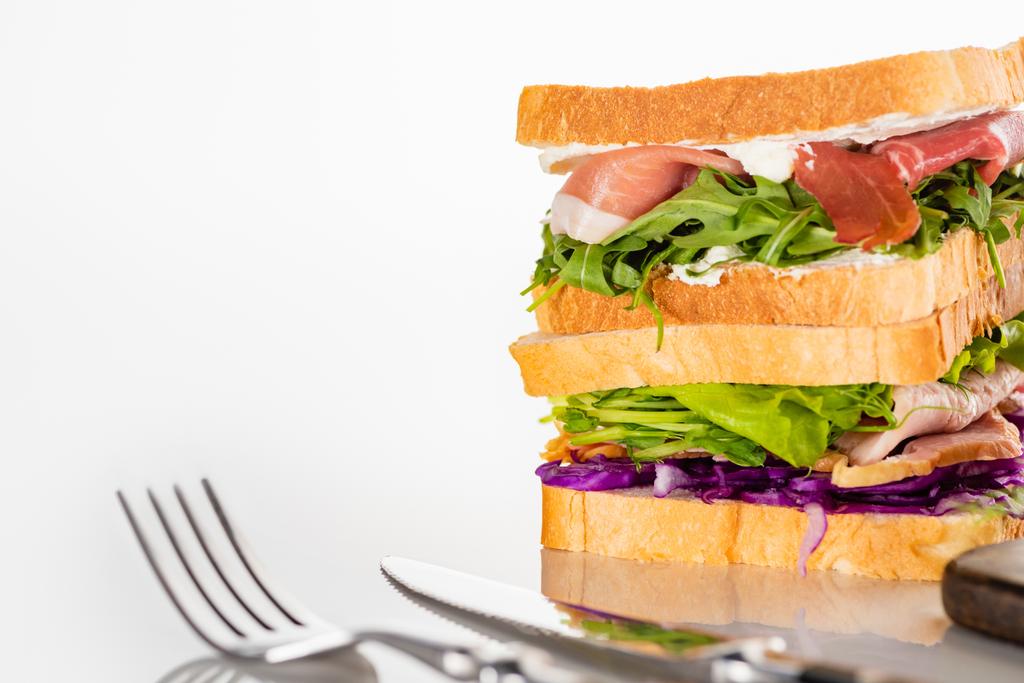 focalizzazione selettiva di sandwich freschi con carne vicino a posate su superficie bianca - Foto, immagini