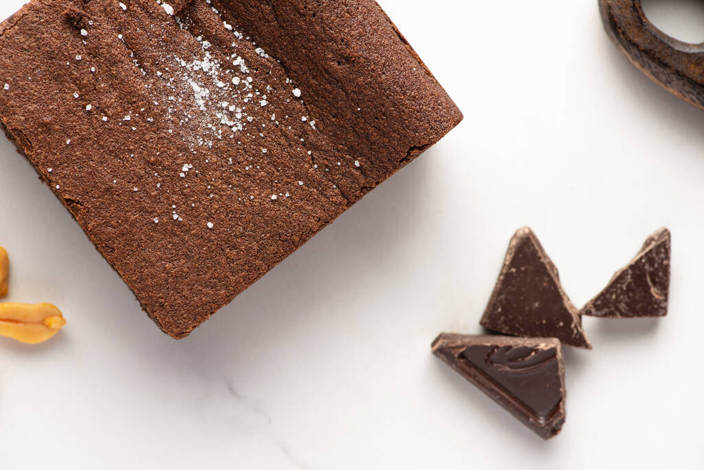 Draufsicht auf köstliche Brownie-Stück in der Nähe von Schokolade auf weißem Hintergrund - Foto, Bild