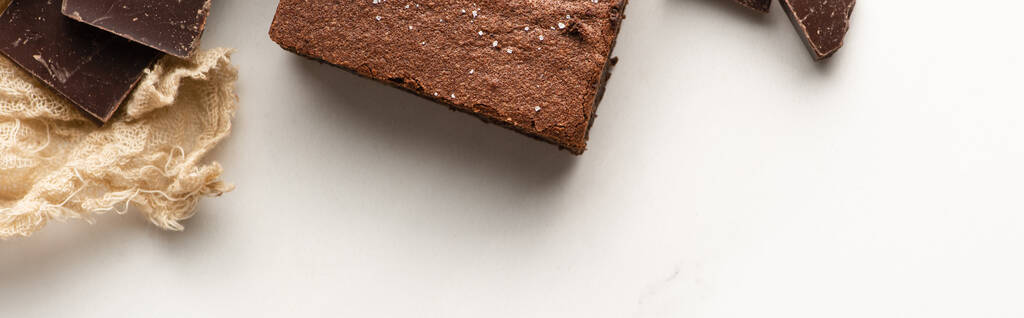 vista superior de la deliciosa pieza de brownie con chocolate sobre fondo blanco, plano panorámico
 - Foto, Imagen