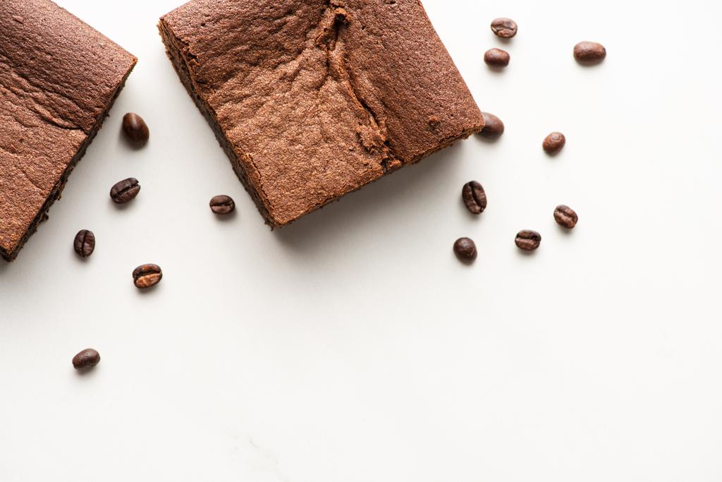 vista dall'alto di deliziosi pezzi di brownie con chicchi di caffè su sfondo bianco - Foto, immagini