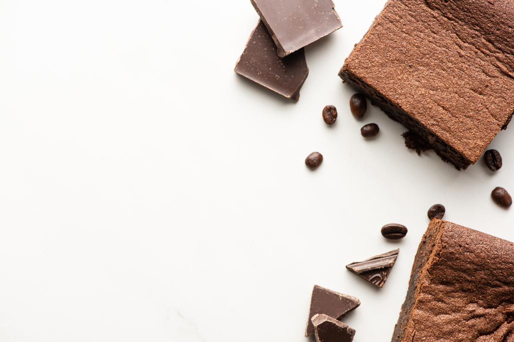 vista superior de deliciosas piezas de brownie con granos de café y chocolate sobre fondo blanco
 - Foto, Imagen