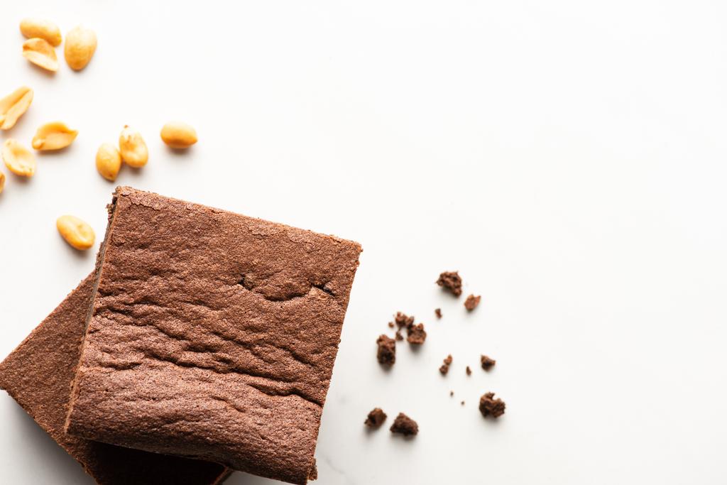 Draufsicht auf köstliche Brownie-Stücke und Erdnüsse auf weißem Hintergrund - Foto, Bild
