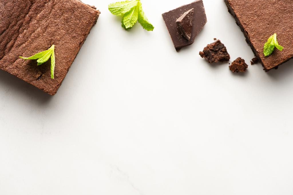 Draufsicht auf köstliche Brownie-Stücke mit Minze und Schokolade auf weißem Hintergrund - Foto, Bild