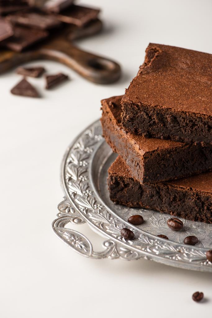 selective focus of delicious brownie pieces on silver tray with coffee beans on white background - Photo, Image