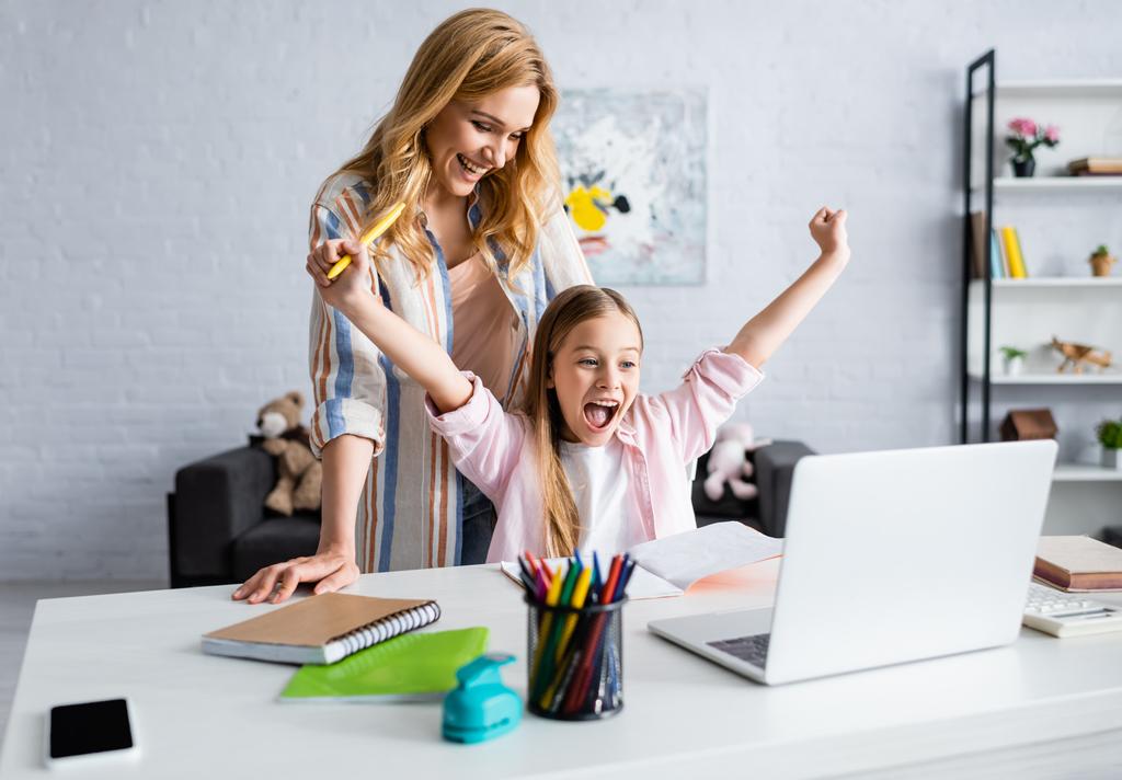 Selektiver Fokus einer lächelnden Mutter, die ein fröhliches Kind anschaut, das während der Online-Ausbildung eine Yah-Geste zeigt  - Foto, Bild
