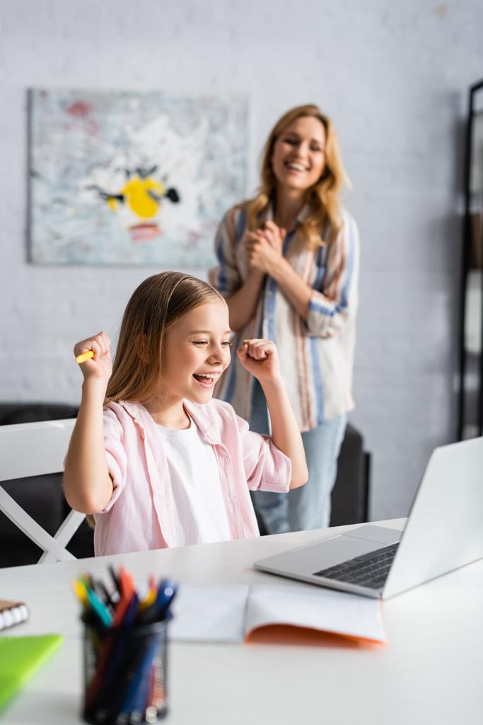 Вибірковий фокус усміхненої дитини, що показує так жест під час онлайн-освіти біля позитивної матері вдома
   - Фото, зображення