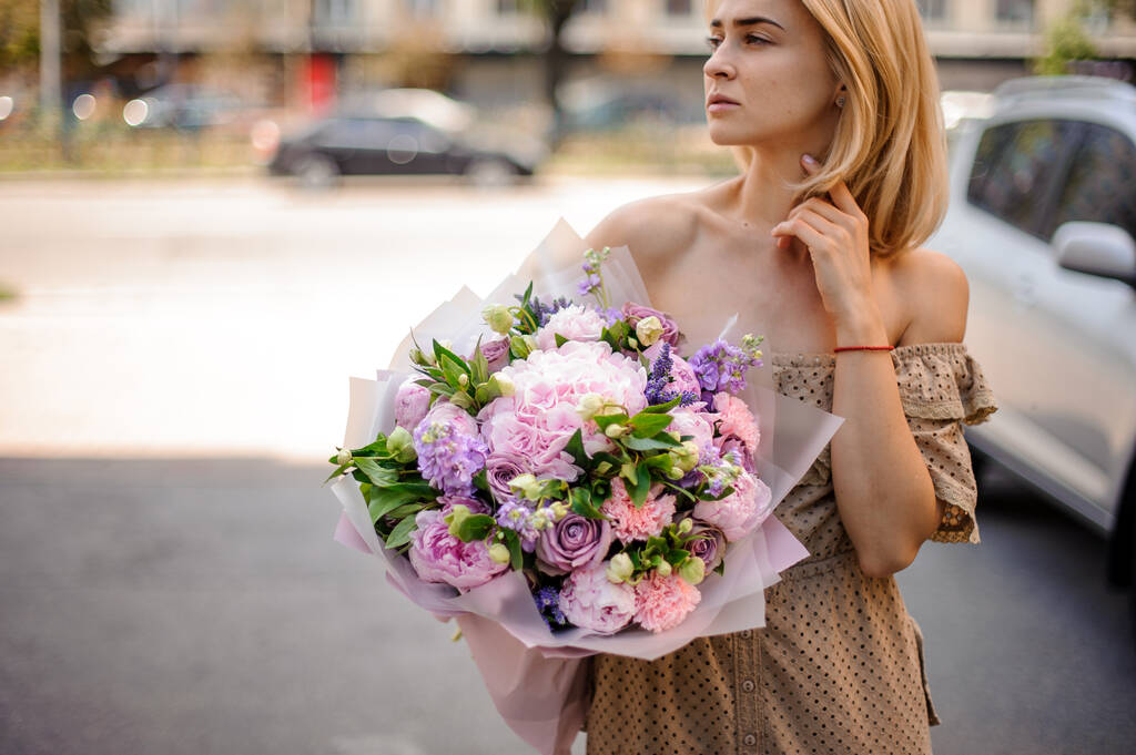 jong aantrekkelijk vrouw houdt teder boeket van bloemen - Foto, afbeelding