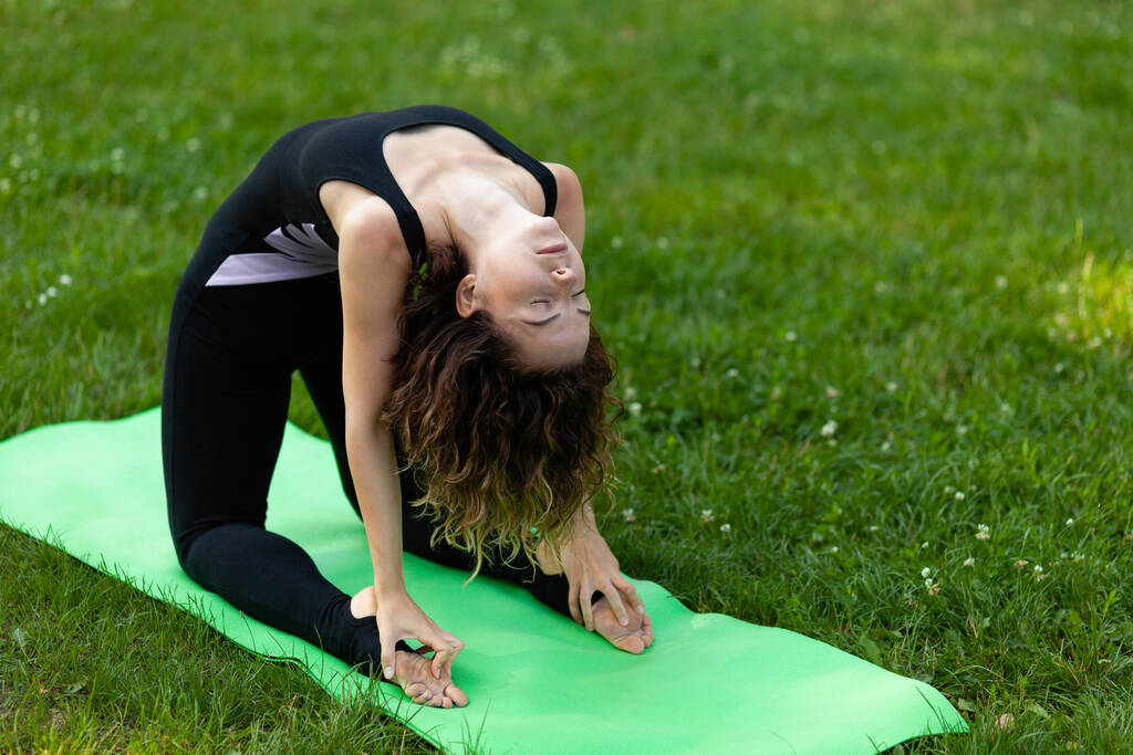Mulher europeia bonita no parque fazendo exercícios de ioga, protege a saúde. Calma e tranquilidade
. - Foto, Imagem
