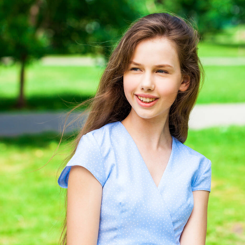 Πορτρέτο μιας νεαρής όμορφης μελαχρινής κοπέλας με μπλε φόρεμα που ποζάρει στο πάρκο - Φωτογραφία, εικόνα