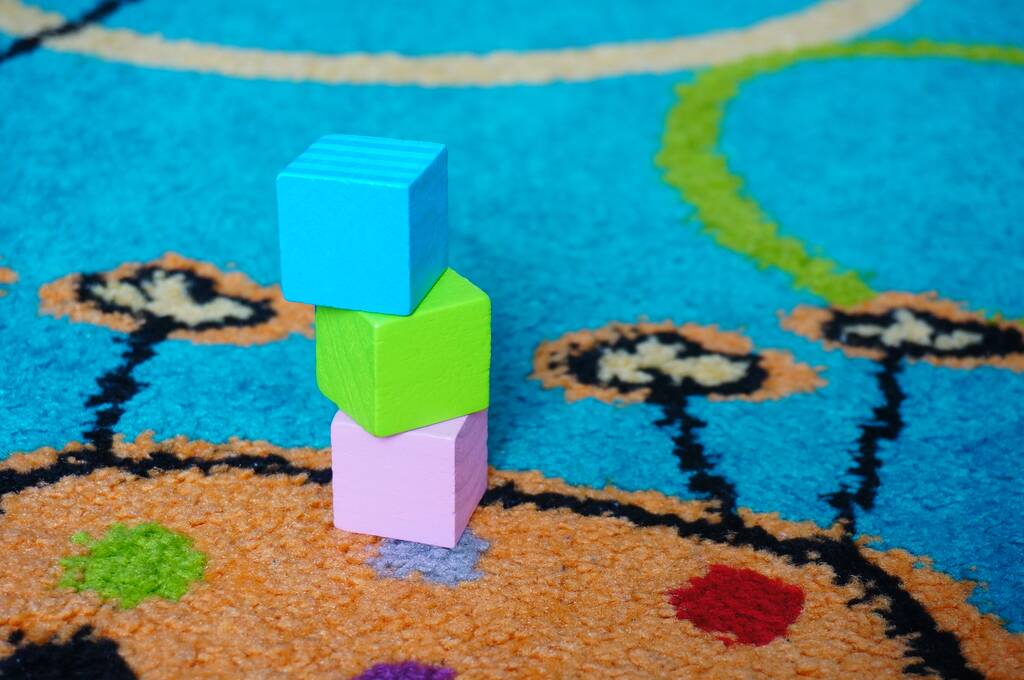 Um tiro de close-up de blocos de brinquedo de madeira azul, verde e rosa em um tapete
 - Foto, Imagem