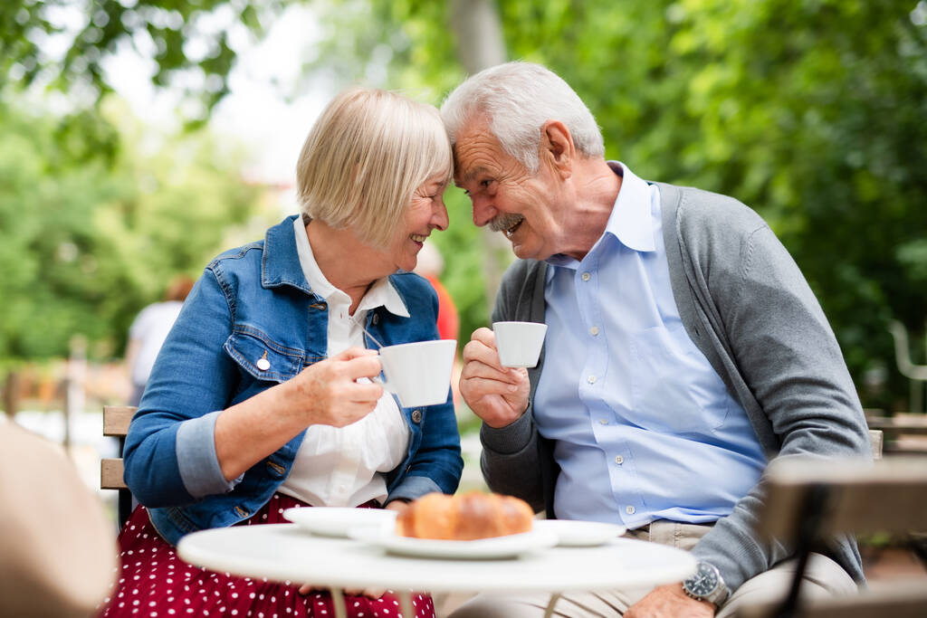 Szczęśliwa para seniorów w miłości siedzi na świeżym powietrzu w kawiarni, zabawy. - Zdjęcie, obraz