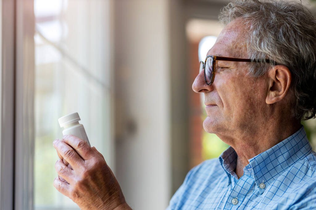 Uomo anziano che prende la medicina di prescrizione a casa - Foto, immagini