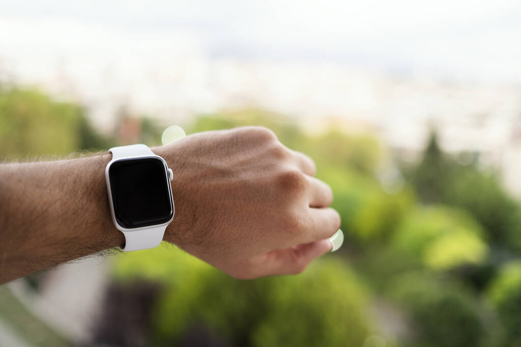 トルコのイズミル- 2020年6月11日:Appleブランドの第5世代ホワイトのショットを閉じる手首と緑の背景に焦点を当てた男性の腕時計. - 写真・画像