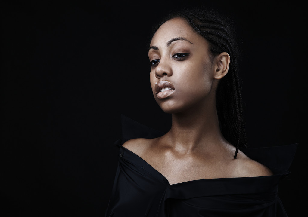 Портрет красивой молодой черной женщины, позирующей на черном фоне
. - Фото, изображение