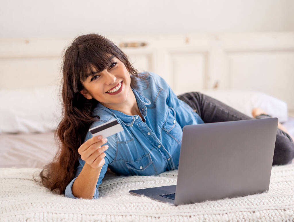 COVID-19 Salgını. Kapatma ve online alışveriş. Kredi kartıyla çekici genç bir kadın dizüstü bilgisayar kullanarak Coronavirus kilitleme ve sosyal uzaklık süresince evdeki internetten yemek alıyor.. - Fotoğraf, Görsel