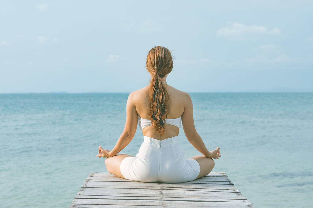 Повернення поглядів жінка практикує йога лотос позу для медитації літніх канікул на пірсі з морським пляжем відчуває таке щастя і веселість, Подорожі в тропічному пляжі Таїланд, вакууми і релаксація Концепція
 - Фото, зображення
