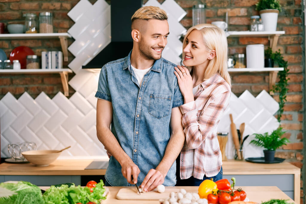 Hymyilevä nuori pari ruoanlaitto yhdessä kasvisruokaa keittiössä kotona - Valokuva, kuva