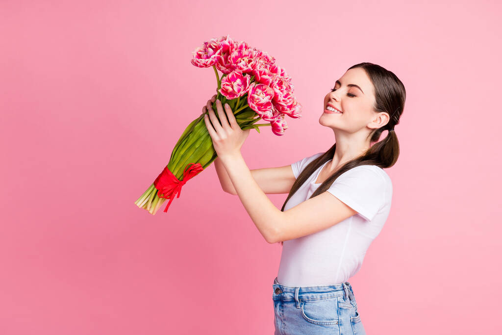 Portrait d'elle elle belle attrayante jolie jolie charmante fille joyeuse rêveuse tenant dans les mains tas de fleurs romantiques sentant isolé sur fond rose couleur pastel - Photo, image